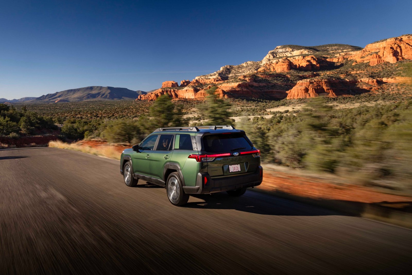 Green 2027 Subaru Outback driving past red rock formations
